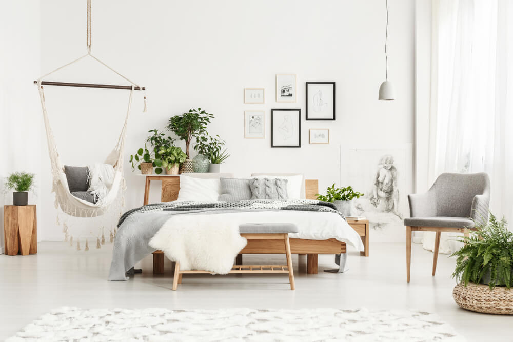 Quarto de casal com decoração minimalista em tons neutros, flores e quadros decorativos.