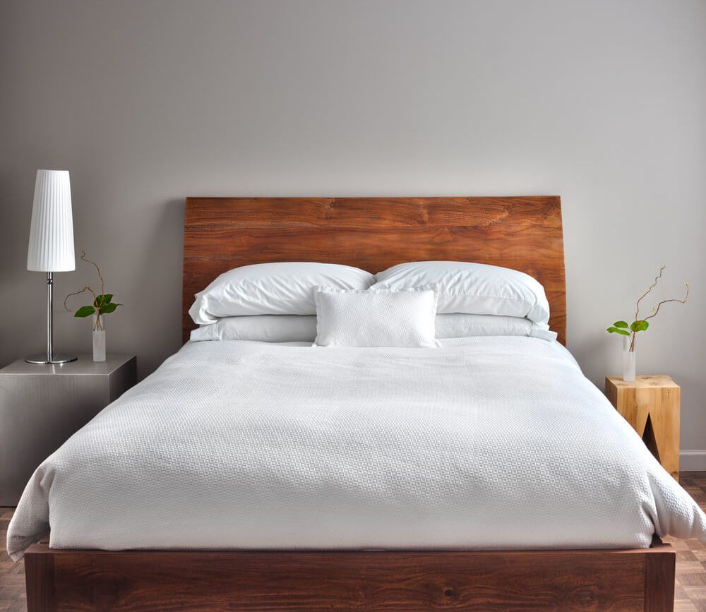 Cama de madeira, com a cabeceira fazendo parte de toda a estrutura