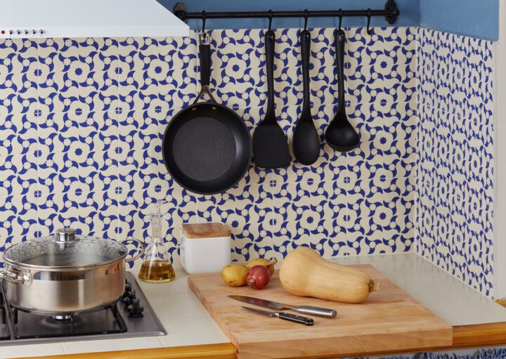 Cozinha revestida com azulejo português com utensílios de cozinha pendurados em ganchos.