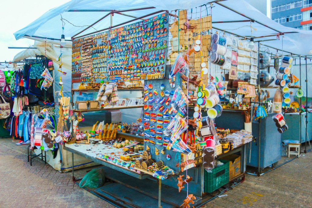 Foto de uma das barracas que tinha na Feirinha da Beira Mar. Nela há diferentes itens de recordação como ímãs de geladeira, chocalhos e outros artesanatos.