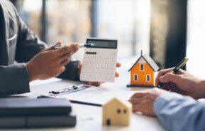 foto que ilustra duas pessoas conversando e segurando uma calculadora