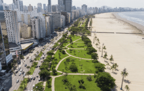 Foto que ilustra matéria sobre orla de Santos mostra a orla da cidade vista de cima, com extensa faixa de areia e uma parte do maior jardim de orla do mundo