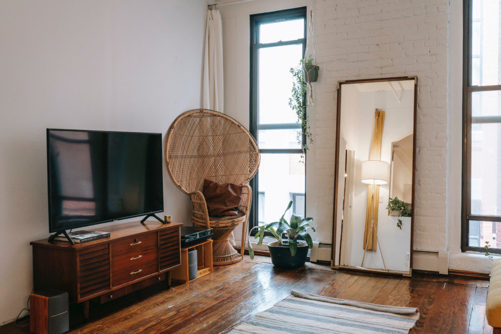 Sala de estar estilo boho com peças em madeira, espelho e decoração rústica. 