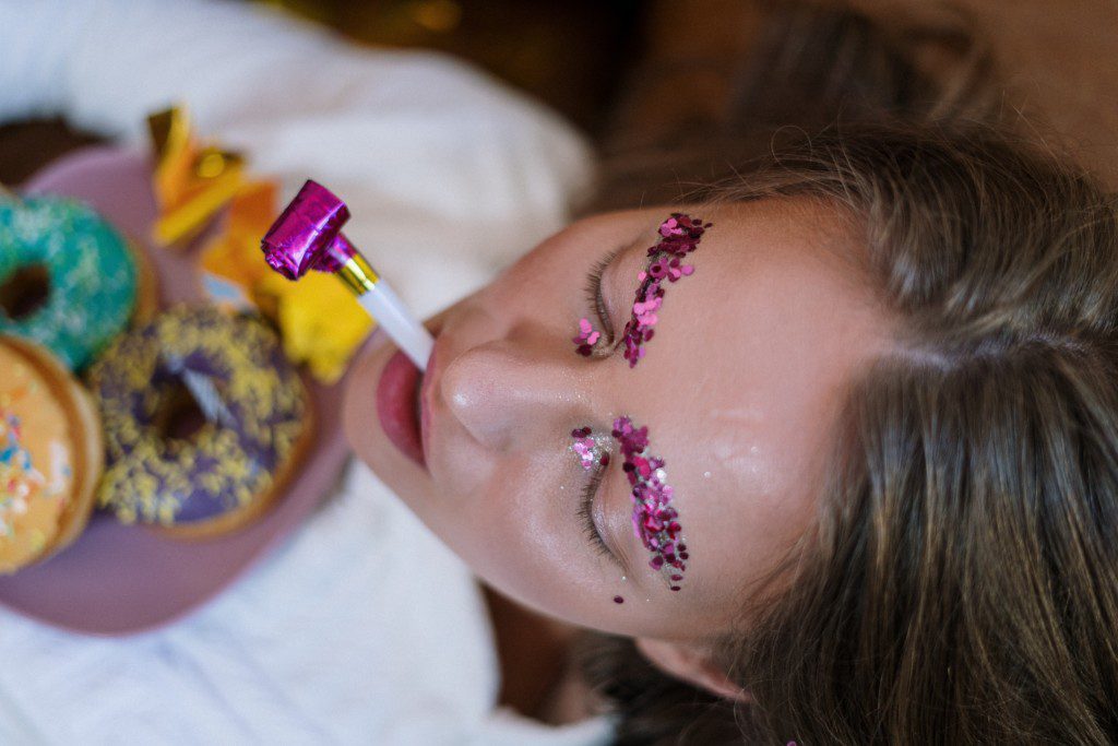 Mulher maquiada para o carnaval segurando uma mascara.