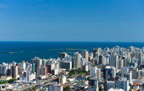 Foto que ilustra matéria sobre bairros de Vila Velha mostra uma visão aérea do bairro Praia da Costa, com muitos prédios e o mar ao fundo. (Foto: Vitor Jubini | MTur)