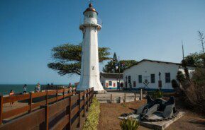 Foto mostra o Farol de Santa Luzia em um dia de sol com céu azul