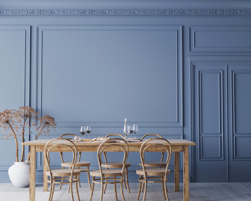Decoração clássica utilizando boiserie em uma parede azul.