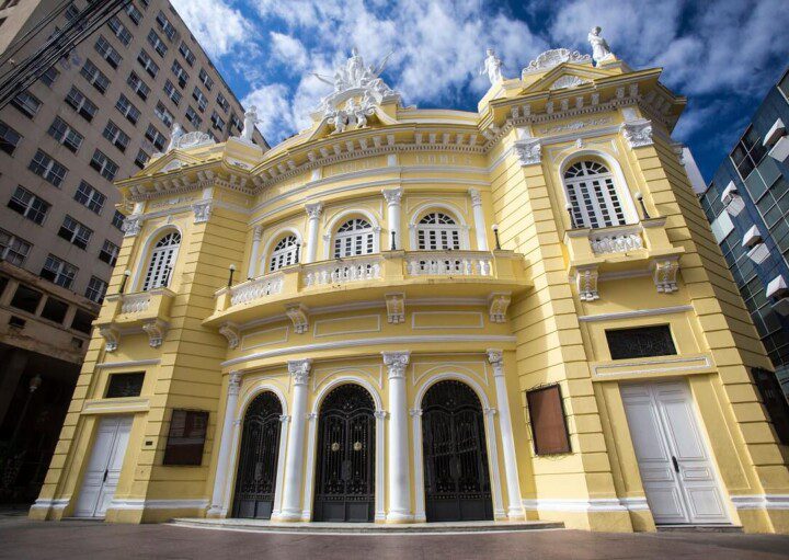 Foto mostra a fachada do Theatro Carlos Gomes em um dia de sol