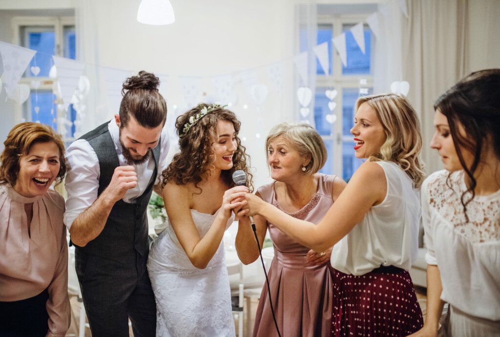 Pessoas festejando e cantando em uma festa de casamento intimista em casa.