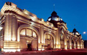 Imagem da fachada do Mercado Municipal de São Paulo a noite toda iluminada.