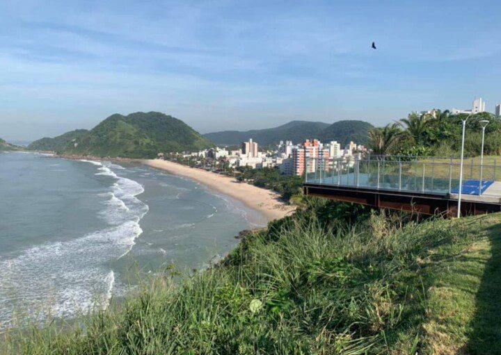 Imagem de um dos mirantes do Guarujá com estrutura em vidro e vista para a praia.