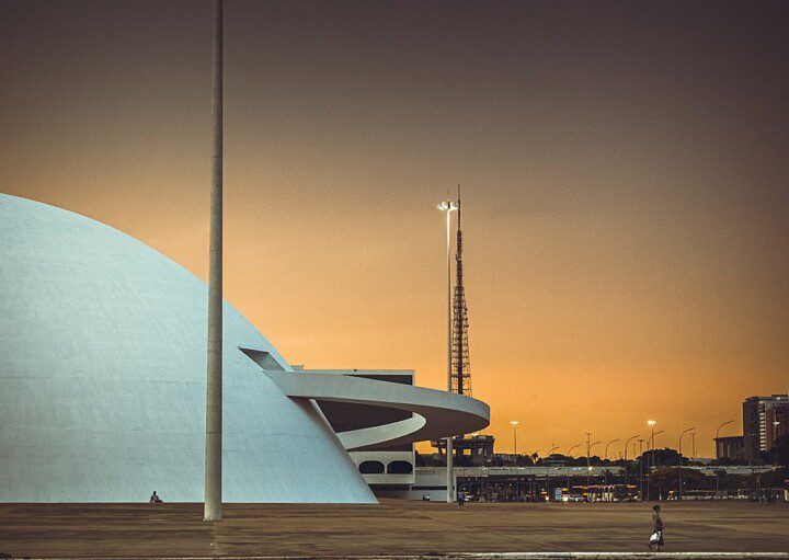 Foto mostra a lateral do Compplexo Cultural da República com o céu alaranjado do cair da noite ao fundo