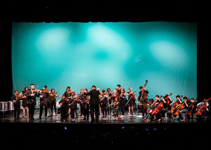 Foto que ilustra matéria sobre o Teatro Municipal de São José dos Campos mostra o interior do espaço com uma orquestra tocando no palco