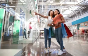 Imagem de uma mãe acompanhada da filha que está apontando para uma vitrine de uma loja de shopping para ilustrar matéria sobre shopping de Praia Grande, no litoral de São Paulo