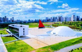 Foto que ilustra matéria sobre o Centro Cultural Oscar Niemeyer mostra o complexo visto de cima em um dia de céu azul com nuvens brancas ao fundo.