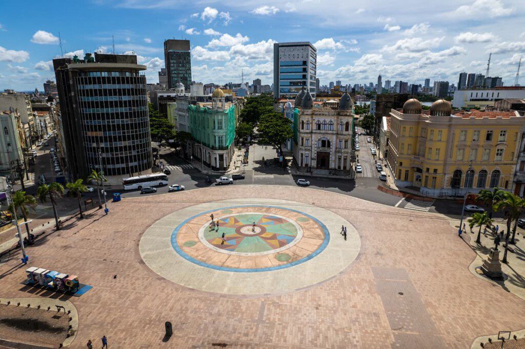 Foto aérea da Praça do Marco Zero, em Recife. É possível ver prédios modernos e históricos, ao redor da praça.