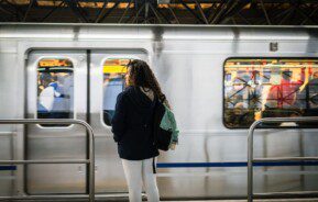 Garota aguarda o metrô parar na estação para embarcar.