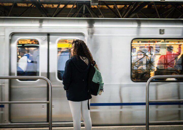 Garota aguarda o metrô parar na estação para embarcar.