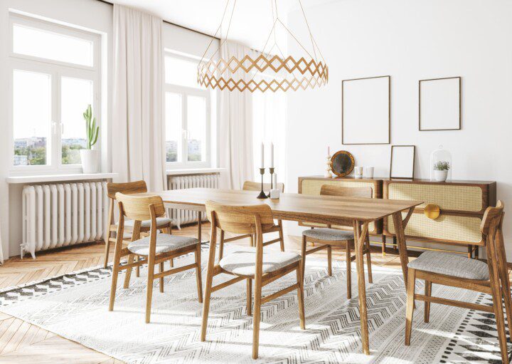 Mesa de jantar em madeira clara em um ambiente clean com paredes brancas, quadros e lustre.