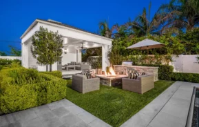 Imagem do quintal de uma casa com cadeiras ao redor de uma fogueira ao lado de um jardim e uma edícula para ilustrar matéria sobre edícula