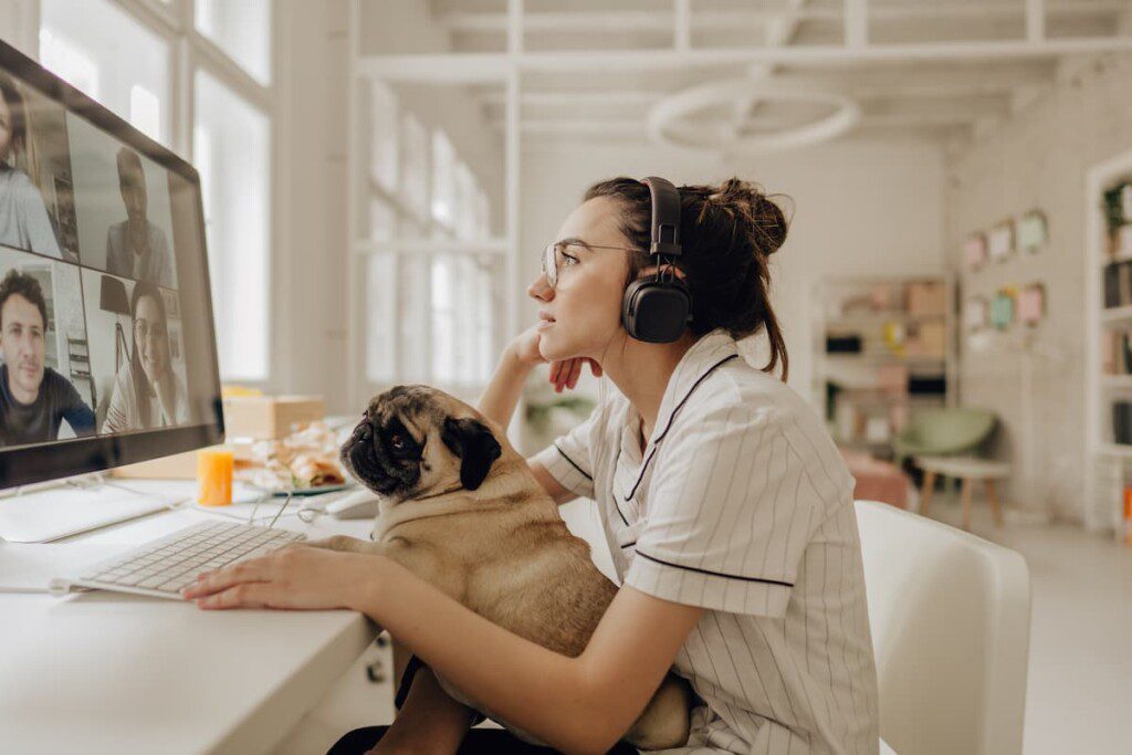 Cachorro no colo de uma mulher trabalhando de home office.