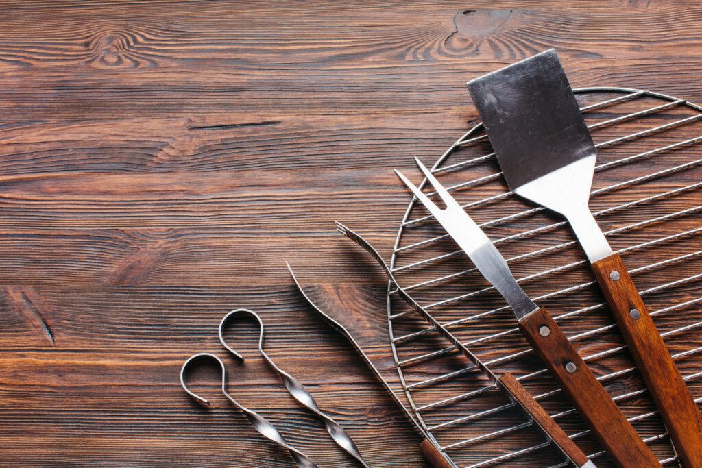 Ferramentas para manusear a carne com segurança no cantinho do churrasco sobre um fundo de madeira