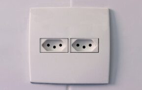 Foto que ilustra matéria sobre voltagem mostra uma tomada do padrão brasileiro de três pontas com duas entradas
