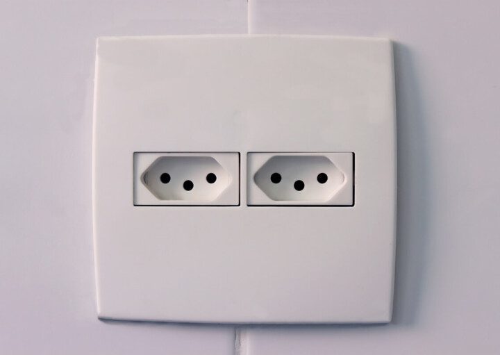 Foto que ilustra matéria sobre voltagem mostra uma tomada do padrão brasileiro de três pontas com duas entradas