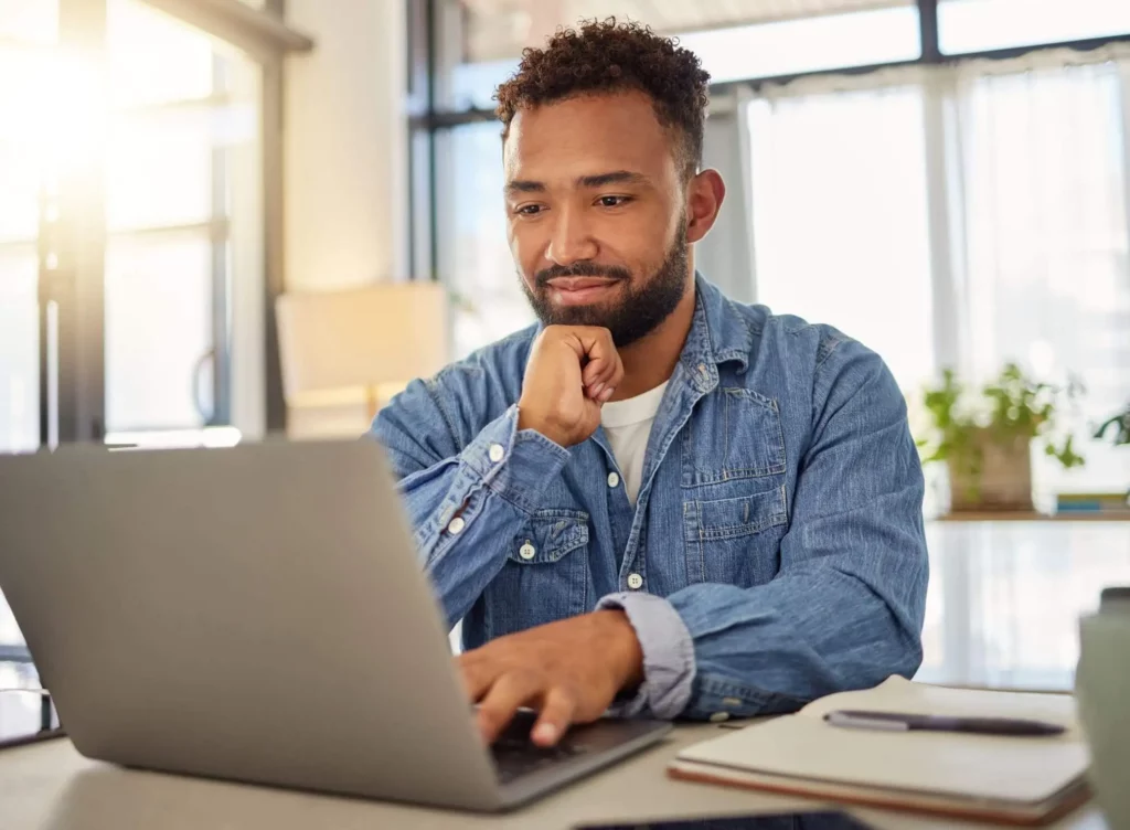 Imagem de um homem trabalhando em seu notebook em casa sentado na mesa para ilustrar matéria sobre como consultar habite-se pela internet