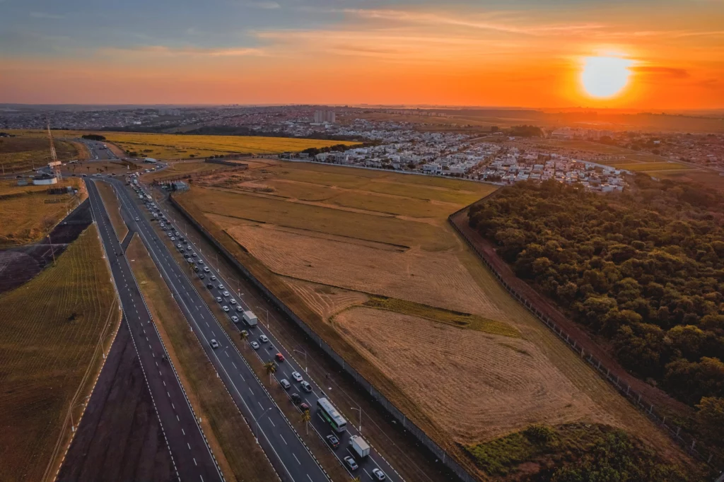 Imagem da vista aérea de Paulínia, no interior de SP, mostra empreendimentos, avenidas, carros e vegetação da cidade durante o pôr do sol para ilustrar matéria sobre as cidades do interior de São Paulo