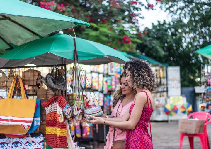 Imagem de duas molheres olhando produtos de artesanato em uma feira de rua para ilustrar matéria sobre as feiras em SP