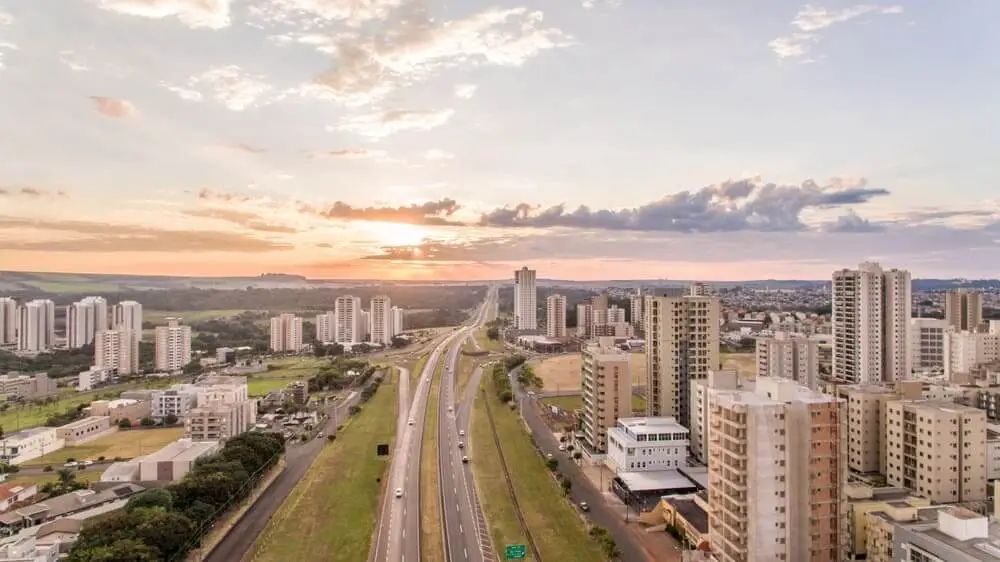 Imagem da vista aérea de Ribeirão Preto mostra prédios e vias da cidade durante o pôr do sol para ilustrar matéria sobre lugares para conhecer no interior de SP. Foto: Shutterstock