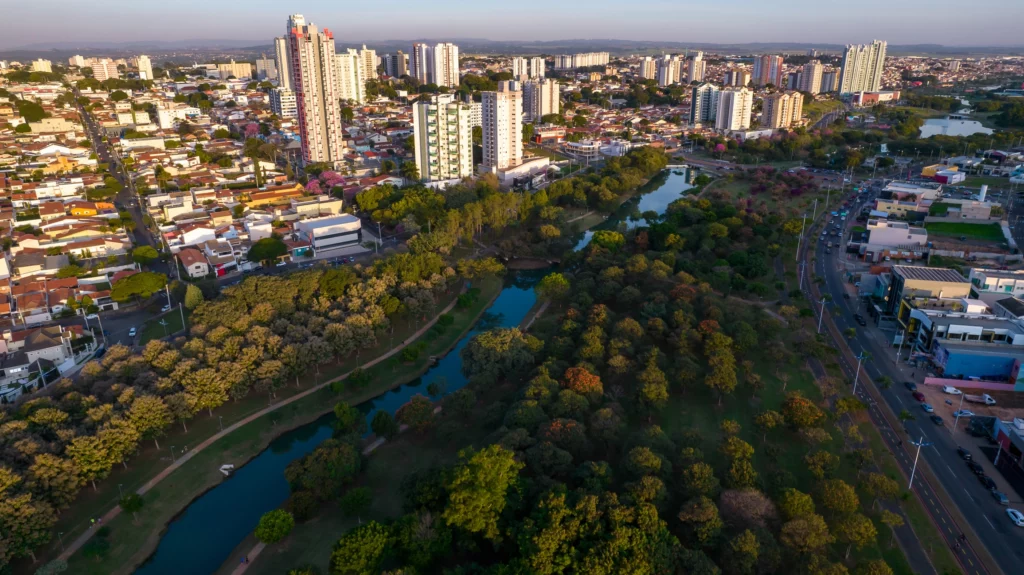 Imagem da vista aérea do Parque Ecológico Indaiatuba, prédios, casas e vegetação ao redor em um dia de céu azul para ilustrar matéria sobre as melhores cidades do interior de SP