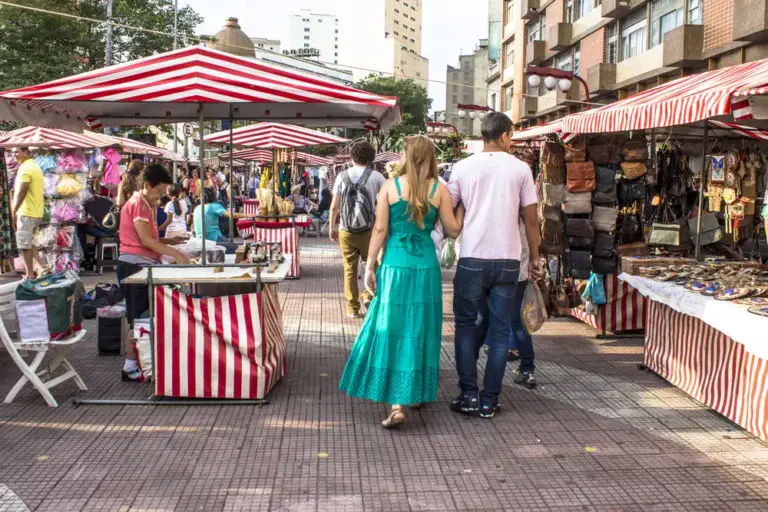 Imagem das barracas da Feira da Liberdade dispostas na rua enquanto o público caminha entre as opções comerciais ao ar livre para ilustrar matéria sobre as melhores feiras em SP