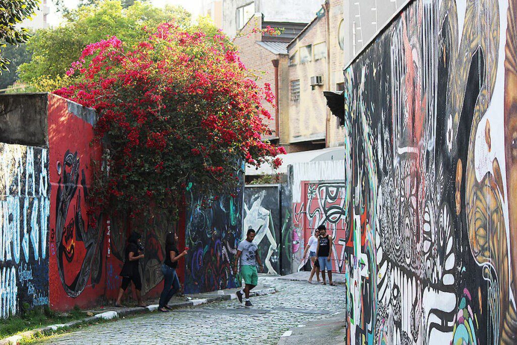 Pessoas passeiam pelos muros grafitados no Beco do Batman. 