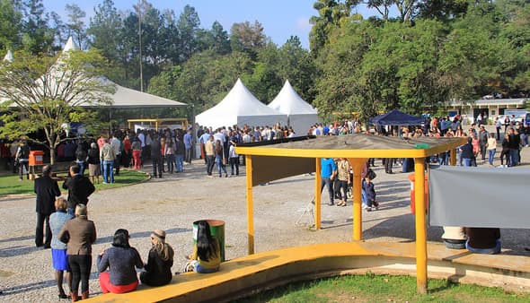 Pessoas circulam entre tendas, em um pátio do Parque Ecológico.