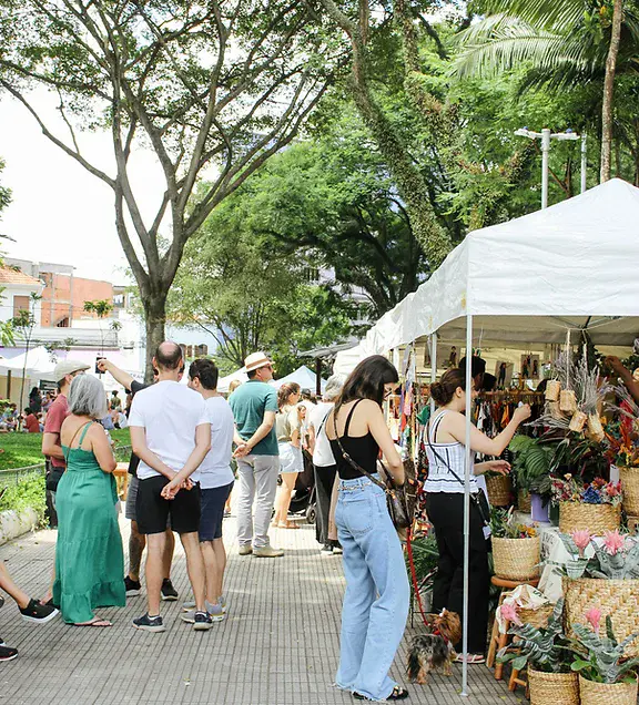 Imagem de pessoas visitando as barracas da Feira Jardim Secreto, uma opção entre as feiras em SP para explorar na capital do estado, para ilustrar matéria sobre onde tem feira em São Paulo
