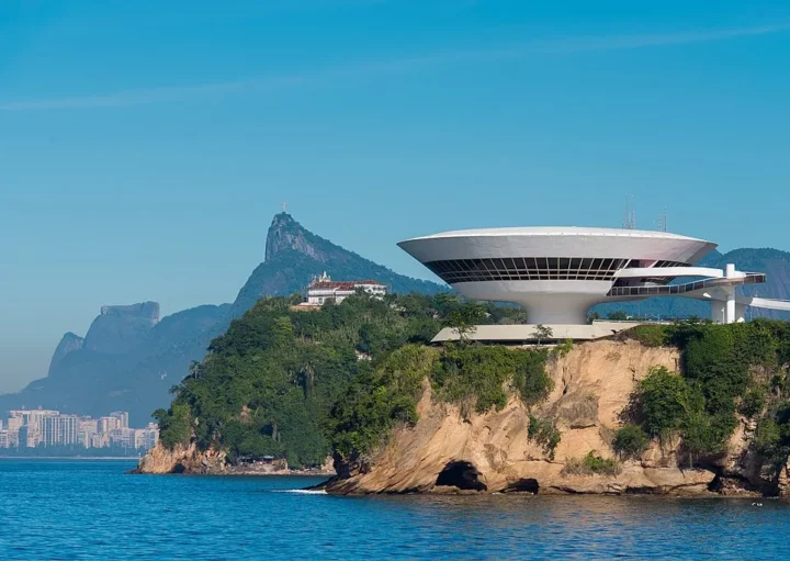 Foto mostra o Museu de Arte Contemporânea de Niterói, com o morro do Corcovado ao fundo (Crédito: WikiCommons)