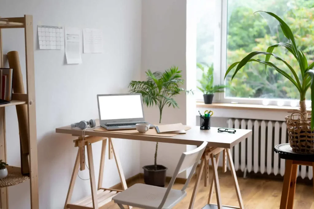 Imagem de um espaço para trabalho em frente a um janelão com plantas para ilustrar matéria sobre apartamento com espaço para home office