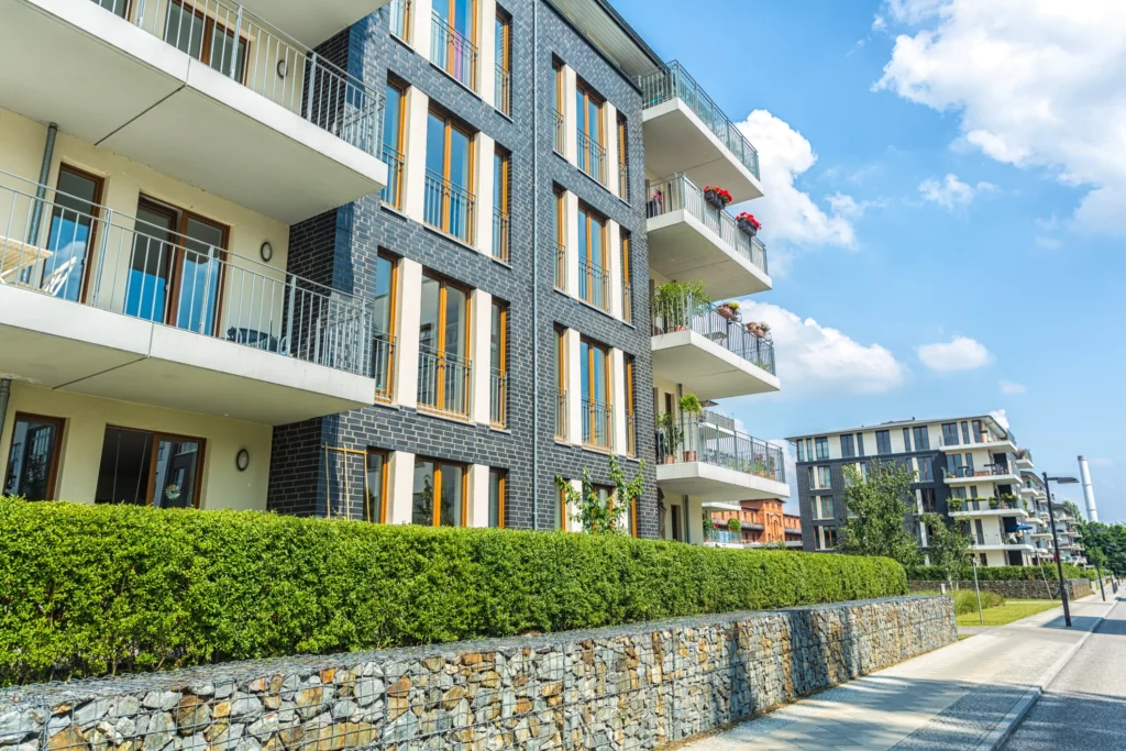 Imagem de um prédio residencial cercado por um gramado verde na parede para ilustrar matéria sobre apartamento térreo