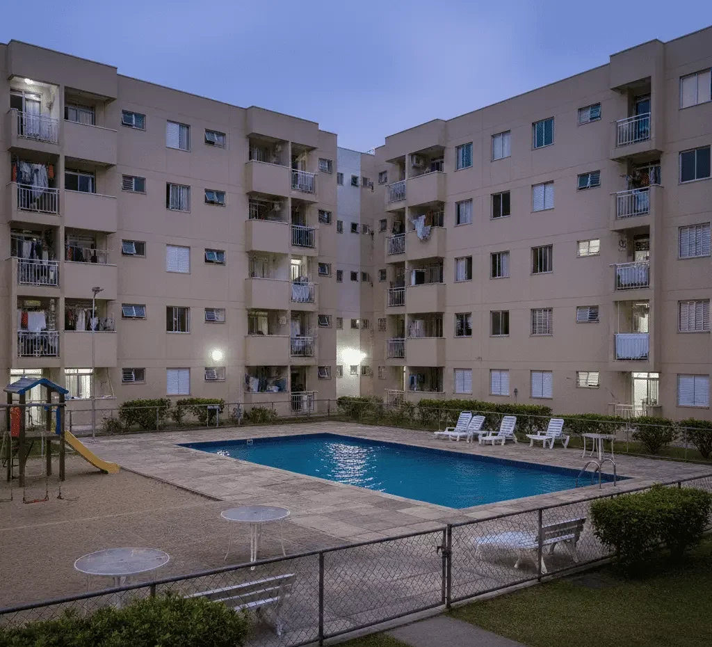 Imagem gerada por inteligência artificial mostra um complexo de apartamentos com prédios bege e uma piscina externa cercada.