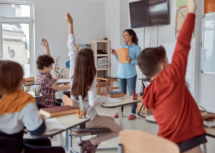 Imagem de uma sala de aula com alunos de costas sentados em carteiras em frente a uma professora para ilustrar matéria sobre as melhores escolas da Zona Oeste de SP