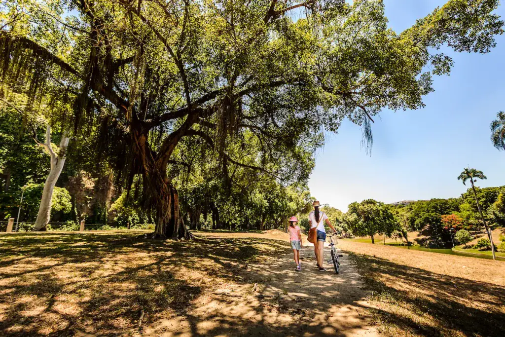 Imagem panorâmica de uma mãe caminhando com a filha entre árvores em um parque para ilustrar matéria sobre o parque Quinta da Boa Vista