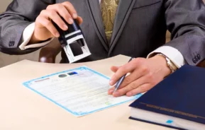 Um homem que, provavelmente, trabalha em um cartório, carimba uma procuração para venda de imóveis.