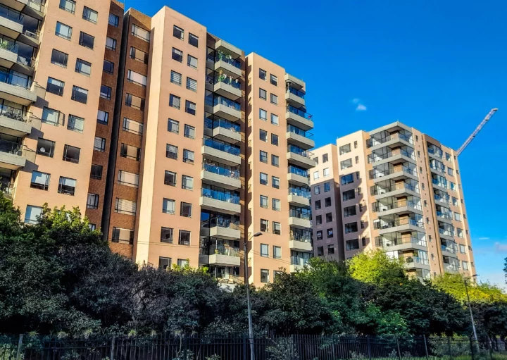 Imagem de três edifícios residenciais com avenidas bem arborizadas e céu azul para ilustrar matéria sobre como escolher o andar do apartamento