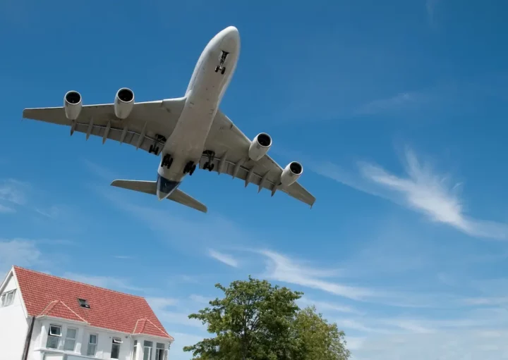 Avião passa por cima de uma casa próxima a um aeroporto.