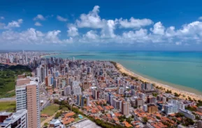 Imagem da vista aérea urbana de João Pessoa mostra mar, orla, prédios e vegetação para ilustrar matéria sobre as cidades mais seguras do Nordeste