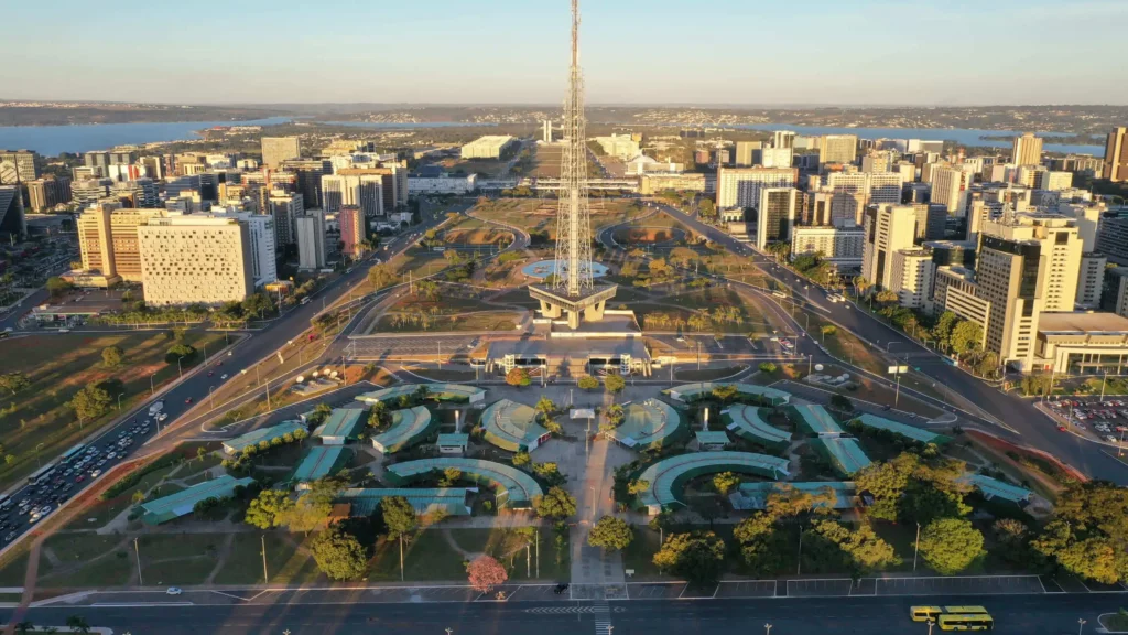 Imagem da vista aérea do Eixo Monumental, em Brasília, mostra paisagismo da Torre de TV e prédios ao fundo em um dia de céu azul para ilustrar matéria sobre o melhor estado para se viver no Brasil