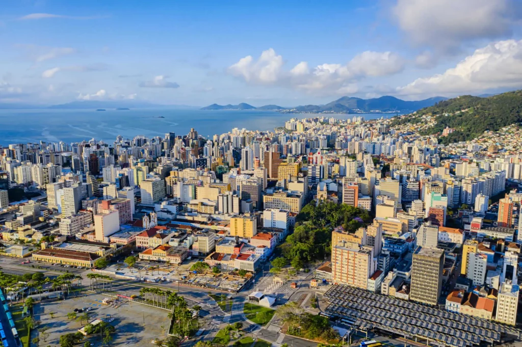 Imagem da vista aérea de Florianópolis, em Santa Catarina, mostra paisagem urbana da cidade com prédios, avenidas, vegetação e mar ao fundo para ilustrar matéria sobre os melhores estados do Brasil para morar