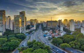 Imagem aérea de carros em pistas cercadas de árvores e prédios durante o anoitecer em São Paulo para ilustrar matéria sobre as cidades com melhor infraestrutura do Brasil